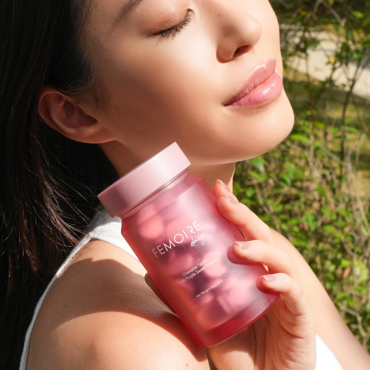Woman holding Femoire Day bottle in natural sunlight